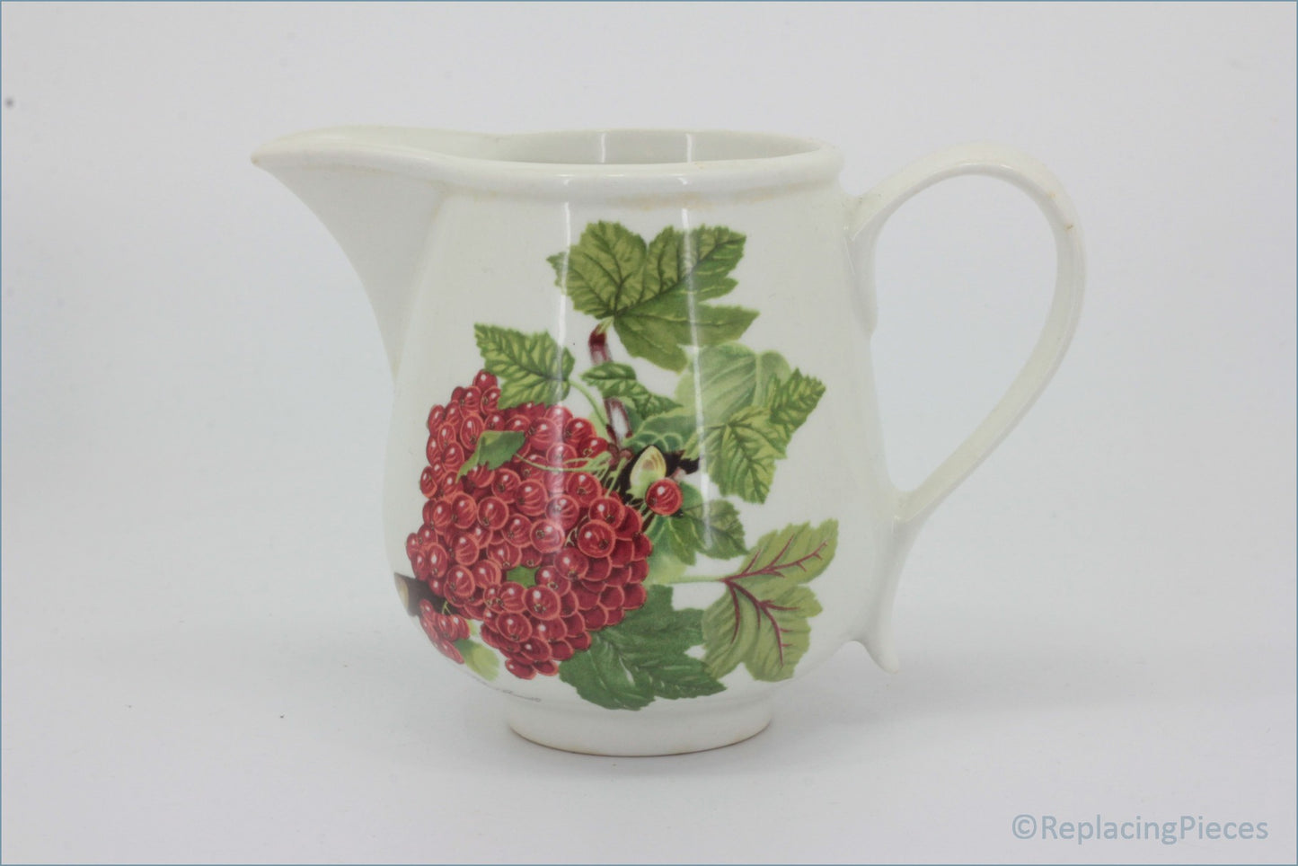 White ceramic pitcher with red berry and green leaf design on a white - Portmeirion - Pomona - Milk Jug (The Red Currant)